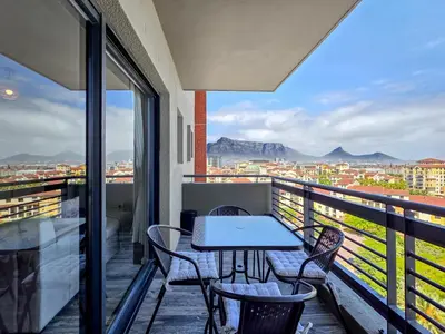 a balcony with a table and chairs and a view at Sea, Canal & Mountain View, Rooftop Jacuzzi & BBQ in Cape Town