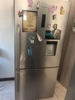 a stainless steel refrigerator with magnets and pictures on it at 22 on breezand in Cape Town
