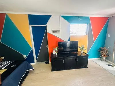a bedroom with a colorful wall with a tv at AAA Luxury Cottages in Cape Town