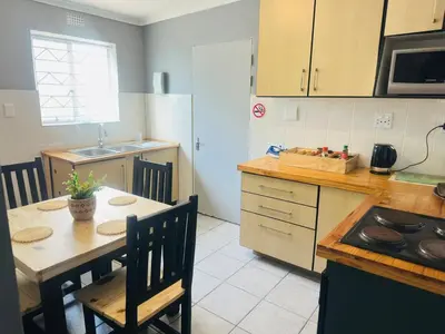 a kitchen with a table and chairs and a kitchen with a stove at AAA Luxury Cottages in Cape Town