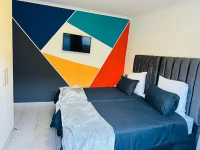 a bedroom with a bed with a colorful wall at AAA Luxury Cottages in Cape Town