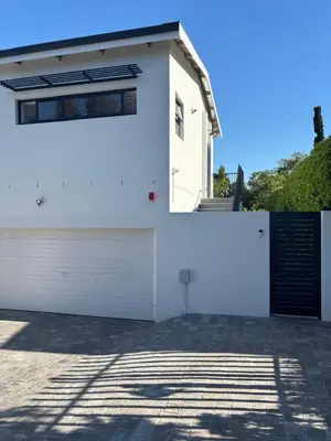 a white building with a door and a garage at 37A Modern Apartment quiet suburb mountain views in Stellenbosch