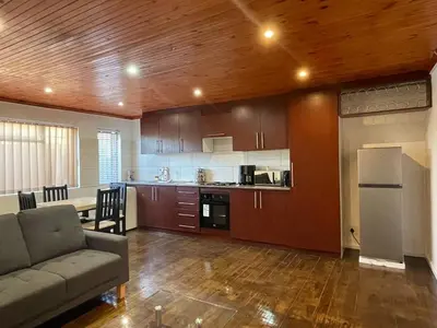 a living room with a couch and a kitchen at AAA Luxury Homes Goodwood Cpt in Elsiesrivier