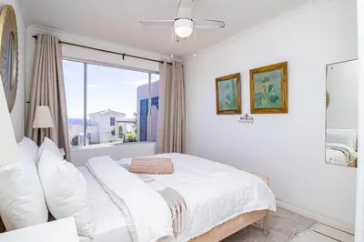a white bedroom with a bed and a window at Nostalgie - Hermanus Beach Club in Hermanus