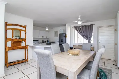a kitchen and dining room with a wooden table and chairs at Nostalgie - Hermanus Beach Club in Hermanus