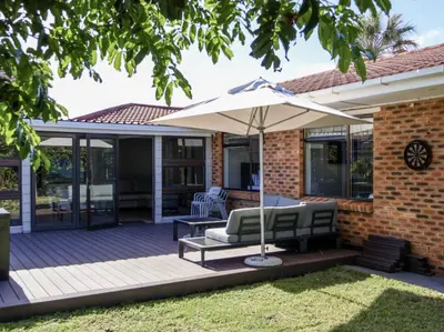 a patio with an umbrella and chairs on a deck at House Nico in Hermanus
