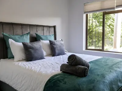 a bedroom with a large bed with blue and white pillows at House Nico in Hermanus