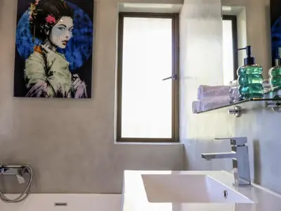 a bathroom with a sink and a painting of a woman at House Nico in Hermanus