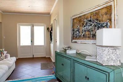 a living room with a green dresser and a painting on the wall at Porcupine Creek in Pringle Bay
