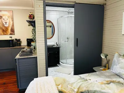 a bathroom with a shower and a bed in a room at Cross Road Cabin in Cape Town