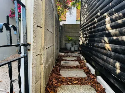 an alley with leaves on the ground next to a building at Cross Road Cabin in Cape Town