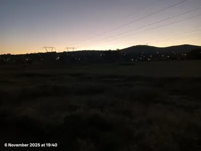 a field at sunset with a city in the background at Sunset View in Durbanville