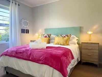 a bedroom with a large bed with a red blanket at Sunset View in Durbanville