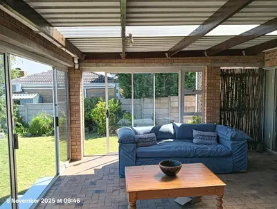 a living room with a blue couch on a patio at Sunset View in Durbanville