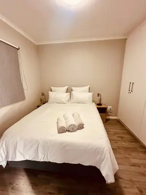 a bedroom with a white bed with towels on it at Table Mountain View Apartment II in Cape Town