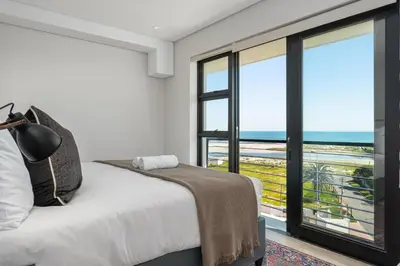 a bedroom with a bed with a view of the ocean at Burmeister Modern 2-Bedroom w/ Views Milnerton in Cape Town