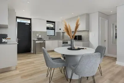 a kitchen and dining room with a white table and chairs at Burmeister Modern 2-Bedroom w/ Views Milnerton in Cape Town