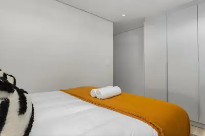 a white bedroom with a bed with a towel on it at Burmeister Modern 2-Bedroom w/ Views Milnerton in Cape Town