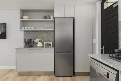 a stainless steel refrigerator in a kitchen with white walls at Burmeister Modern 2-Bedroom w/ Views Milnerton in Cape Town