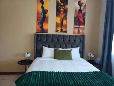 a bedroom with a bed with three paintings on the wall at Oakway Guest House 2 in Kuilsrivier