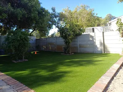 a yard with a fence and green grass at Oakway Guest House 2 in Kuilsrivier