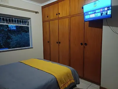 a bedroom with a bed and a flat screen tv at Oakway Guest House 2 in Kuilsrivier