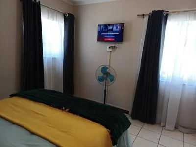 a bedroom with a fan and a window with a tv at Oakway Guest House 2 in Kuilsrivier
