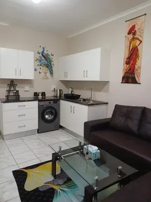 a living room with a couch and a kitchen at Oakway Guest House 2 in Kuilsrivier