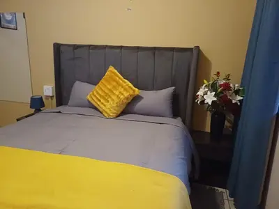 a bedroom with a bed with a yellow pillow and flowers at Oakway Guest House 2 in Kuilsrivier