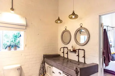 a bathroom with a sink and two mirrors on the wall at The Bay Cottage in Pringle Bay