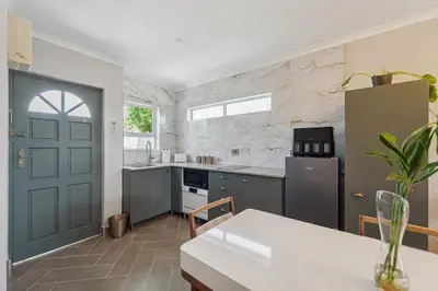 a kitchen with a table and a blue door at Lloyd's Corner in Cape Town