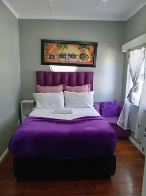 a bedroom with a purple bed and a purple couch at ABC GUEST HOUSEs BELLEVILLE in Bellville