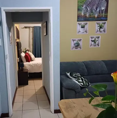 a living room with a blue couch and a bed at OakwayGuestSuit2 Private 1 Bed Kitchen Bath Aircon in Kuilsrivier