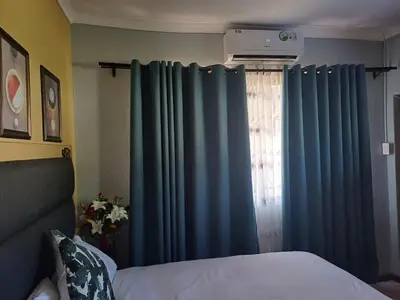 a bedroom with blue curtains and a bed and a window at OakwayGuestSuit2 Private 1 Bed Kitchen Bath Aircon in Kuilsrivier