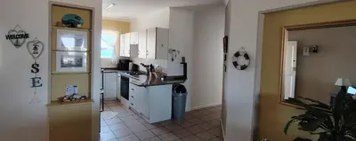 a kitchen with white cabinets and a tile floor at Windy Corner Luxury Apartment in Gordonʼs Bay