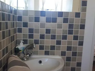 a bathroom with a sink and blue and gray tiles at Windy Corner Luxury Apartment in Gordonʼs Bay