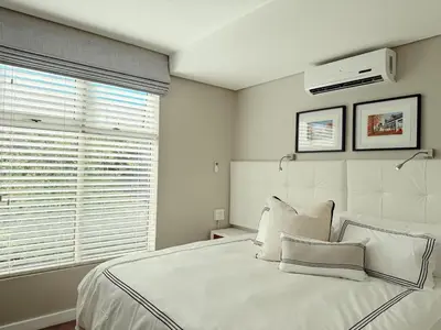 a white bedroom with a large bed and a window at Instellies Self Catering Apartment in Stellenbosch