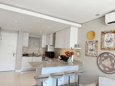a kitchen with white cabinets and bar stools at Instellies Self Catering Apartment in Stellenbosch