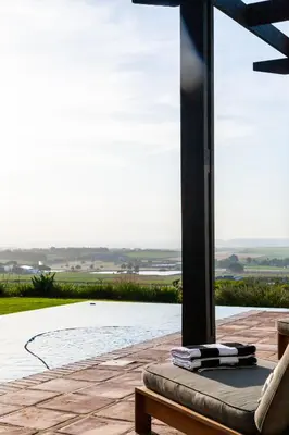 a patio with a couch and a large glass window at Manor at Longridge in Helderberg