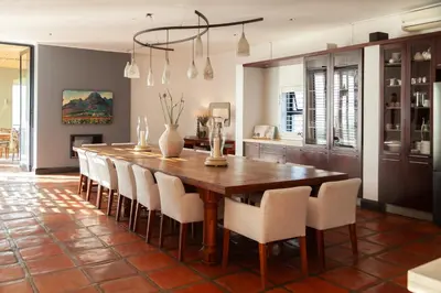 a dining room with a wooden table and chairs at Manor at Longridge in Helderberg