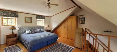 a bedroom with a bed and a staircase with a ceiling at Clarents Cottage in Somerset West