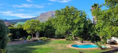 a yard with a swimming pool with a mountain in the background at Clarents Cottage in Somerset West