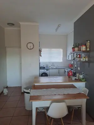 a kitchen with a table and chairs and a clock at Central 3rd Floor Durbanville Apartment in Durbanville