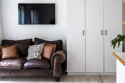 a living room with a brown couch and a mirror at Private Garden Flat in Die Boord with Secure Parking in Stellenbosch