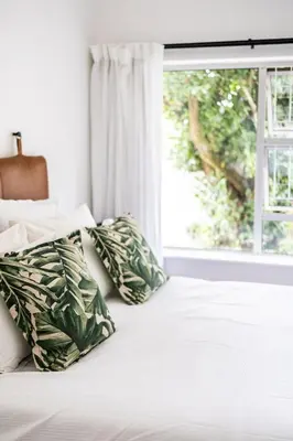 a bedroom with a bed with pillows and a window at Private Garden Flat in Die Boord with Secure Parking in Stellenbosch