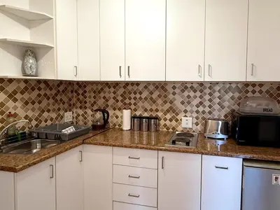 a kitchen with white cabinets and a counter top at Olly-Pops Cottage in Tygerberg Hills