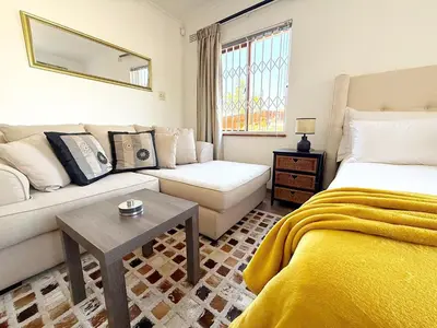 a living room with a bed and a couch at Olly-Pops Cottage in Tygerberg Hills
