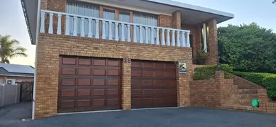 a brick house with a brown garage door at Olly-Pops Cottage in Tygerberg Hills