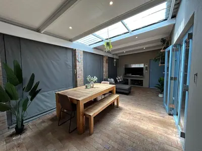 a dining room with a table and a couch at A home away from home near the beach in Strand