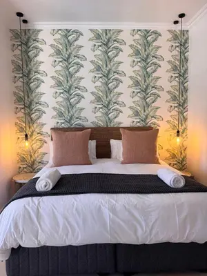 a bedroom with a large bed with a wall at The Boutique Suites by Beach Collection Winelands in Cape Town